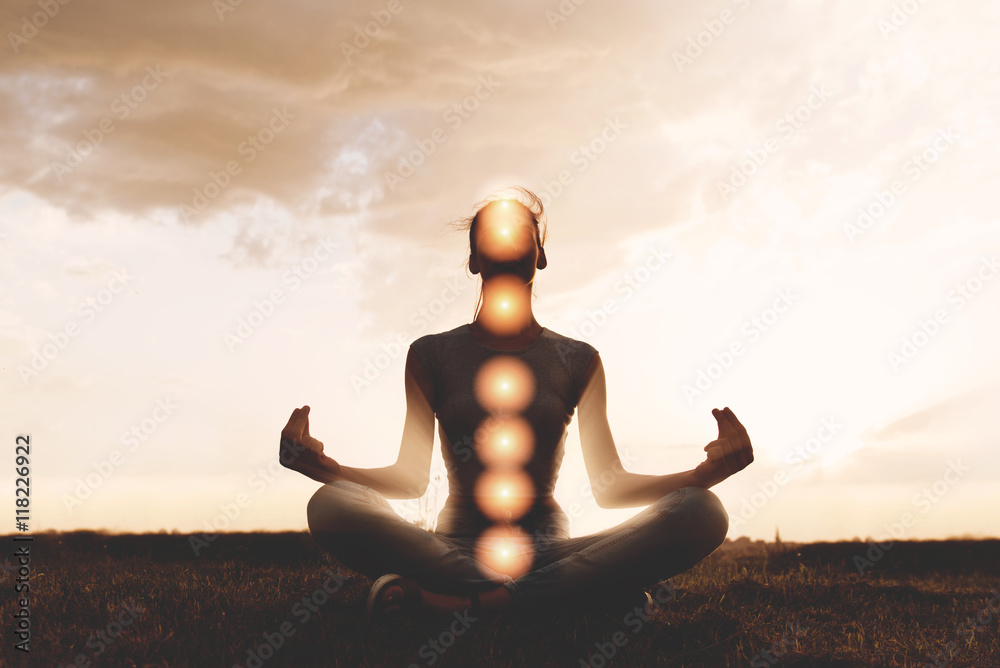 Woman practicing meditation in sunset, with chakras marked - obrazy, fototapety, plakaty 