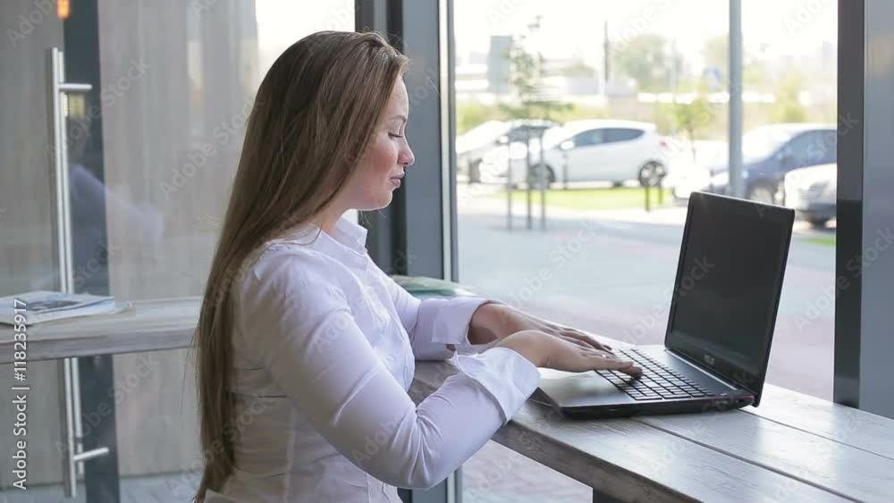 Business woman sitting at a desk using a laptop, drink coffee Business woman sitting at a desk using a laptop, drink coffee