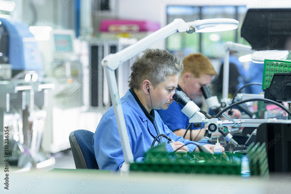Female worker soldering component onto circuit boards in circuit board