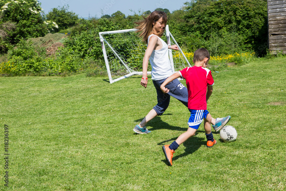 Mother and son playing football in the garden Mother and son playing football in the garden