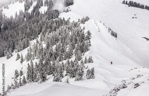 Distant view of male skier walking uphill at Kranzegg, Bavaria, Germany photo