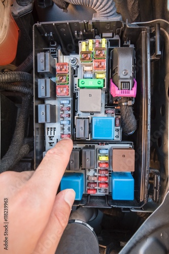 Hand checking a fuse in the fuse box of a modern car engine