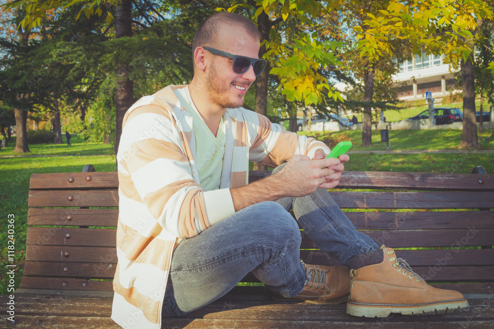 Man using cellphone on a bench in the park. Man using cellphone on a bench in the park.