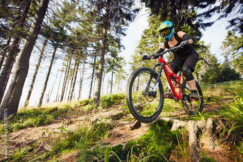 Female mountainbiker riding downhill in forest