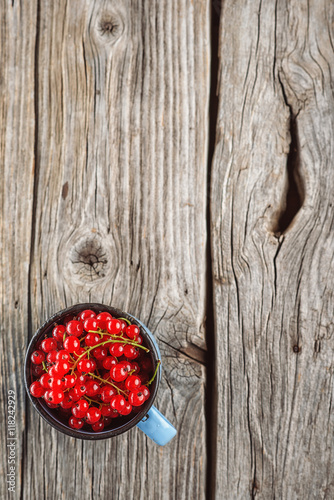 red currants in metal cup on wooden background
