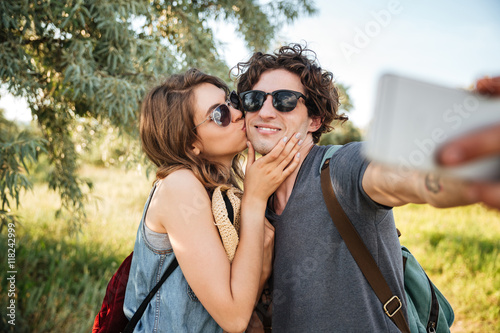 Couple with backpacks hiking in the forest and making selfie