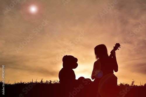 Silhouette children playing with teddy bear on sunset