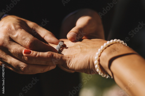Man s hands adjust a wedding ring on bride s hand wearing the pe