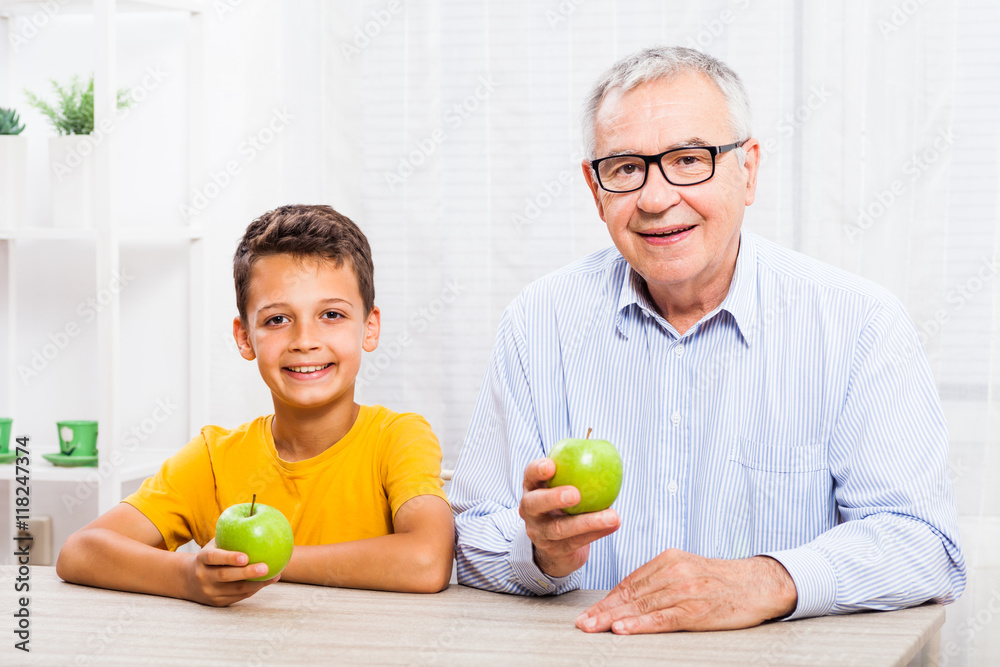 Grandfather and grandson are eating apples at home. Healthy lifestyle. Grandfather and grandson are eating apples at home. Healthy lifestyle.