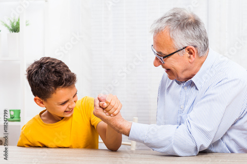 Grandfather and grandson arm wrestle at home.