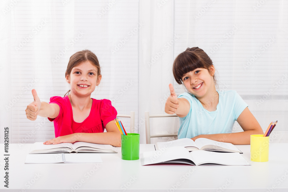 Cute little girls are showing thumbs up while their are doing their homework. Cute little girls are showing thumbs up while their are doing their homework.