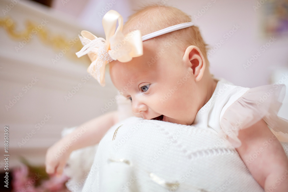 Babygirl in peach bow bites white blanket Babygirl in peach bow bites white blanket