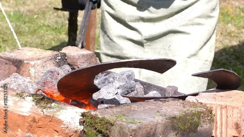 A blacksmith models a bar of iron with hammer after took it from fire forge. photo