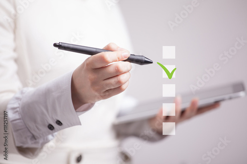 Young business woman checking on checklist box. Gray background.