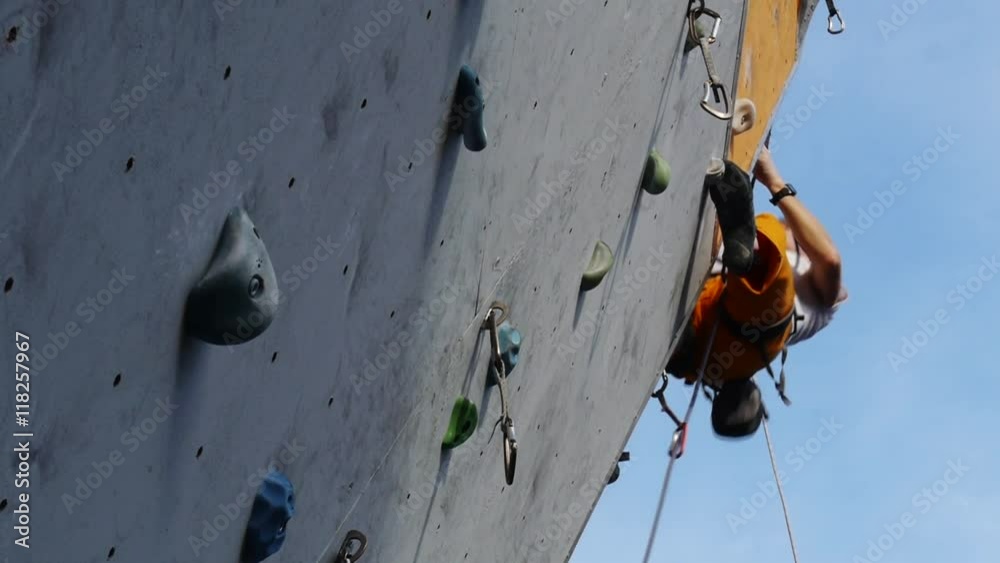 Climbing wall in the open air. Man overcomes route with belay Climbing wall in the open air. Man overcomes route with belay