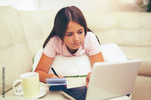 Smiling little girl with laptop computer and headphones at home © Mediteraneo