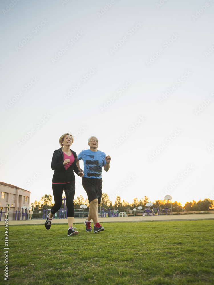 Older couple jogging together in urban park Older couple jogging together in urban park