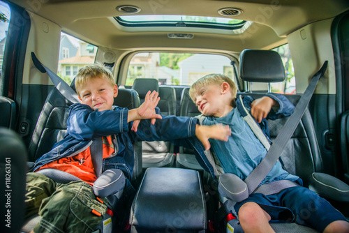 Twin brothers sitting in back of vehicle, fighting photo