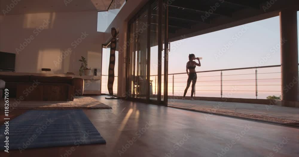 Shot of young woman standing in the balcony and drinking water from bottle. Fitness woman taking break from workout.
Shot of young woman standing in the balcony and drinking water from bottle. Fitness woman taking break from workout.