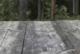 Table made of old wooden planks. Background, green forest blur.
