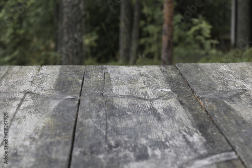 Table made of old wooden planks. Background, green forest blur.