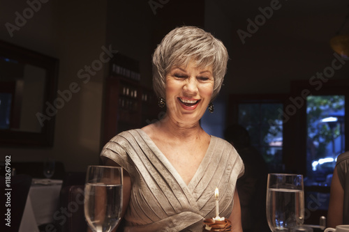 Happy woman blowing out birthday cupcake photo