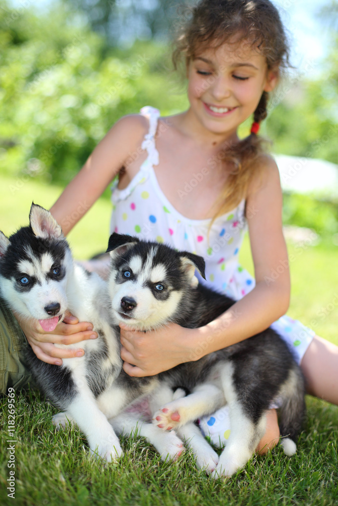 Beautiful girl sitting on the grass with two puppies husky Beautiful girl sitting on the grass with two puppies husky