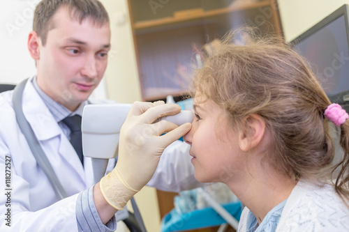 ophthalmologist examines the eyes of a teenage girl