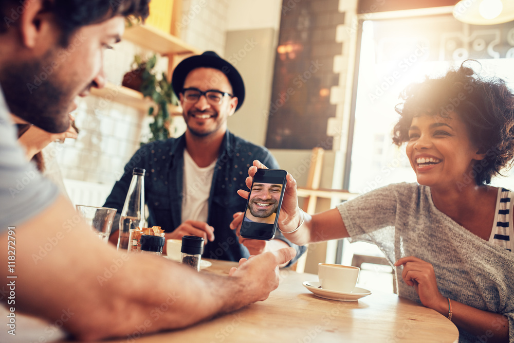 Fototapeta premium Friends in cafe and looking at the photos on smart phone