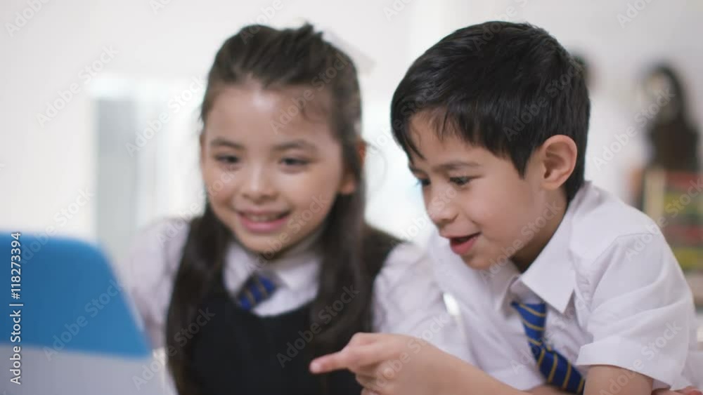 Happy little boy & girl looking at computer in school classroom Happy little boy & girl looking at computer in school classroom