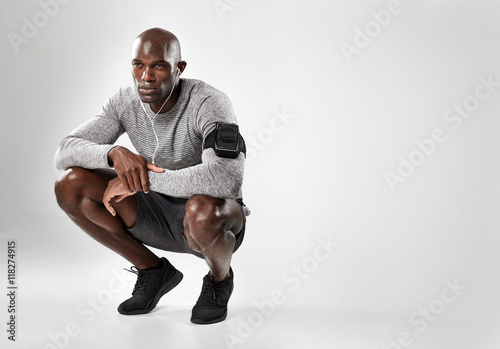 Bilde på lerret Young african man crouching on grey background