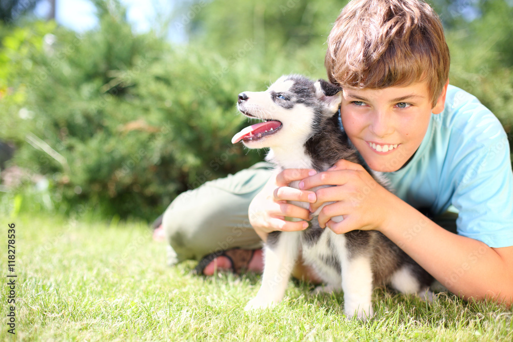 Happy boy sitting on the grass with puppy husky Happy boy sitting on the grass with puppy husky