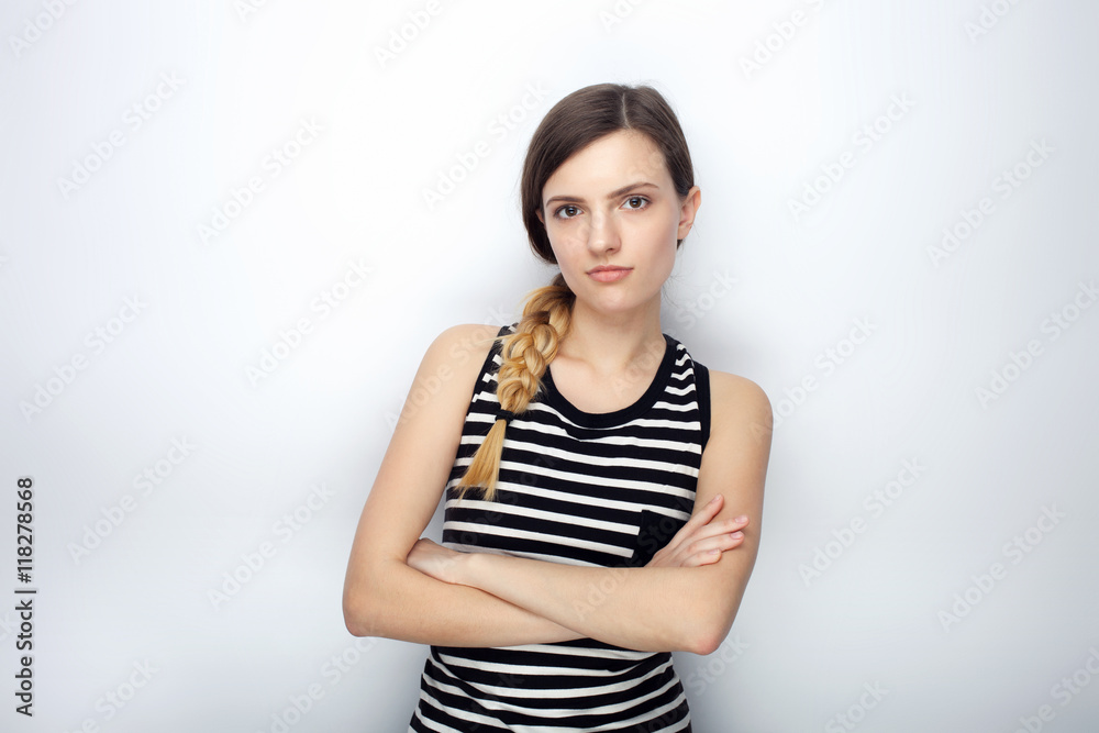 Portrait of serious young beautiful woman in striped shirt crossed hands posing for model tests against studio background Portrait of serious young beautiful woman in striped shirt crossed hands posing for model tests against studio background