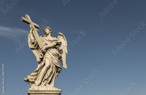 A large, stone statue of an angel, against a deep blue summer sky © parkerspics