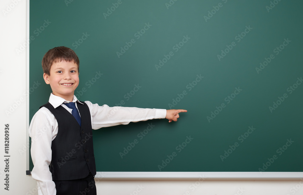 school student boy posing at the clean blackboard, show finger and point at, grimacing and emotions, dressed in a black suit, education concept, studio photo school student boy posing at the clean blackboard, show finger and point at, grimacing and emotions, dressed in a black suit, education concept, studio photo
