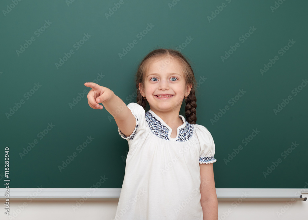 school student girl posing at the clean blackboard, grimacing and emotions, dressed in a black suit, education concept, studio photo