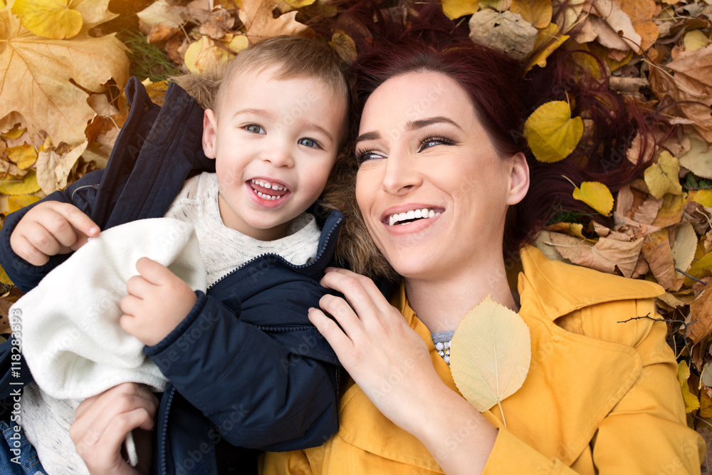 Funny mother and son lying on the leaves Funny mother and son lying on the leaves