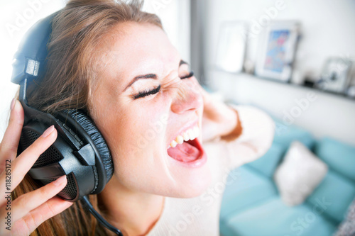 Woman with headphones singing and listening to music at home