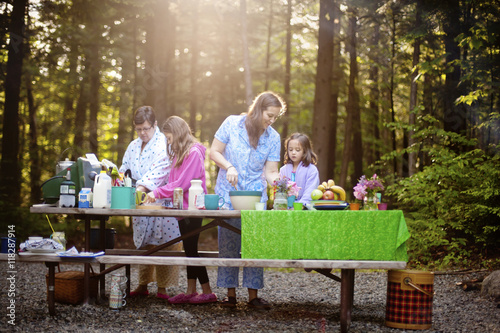 Three generations of Caucasian women cooking at picnic table photo