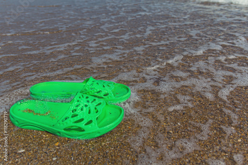 Green slippers lie on the seashore. Recreation