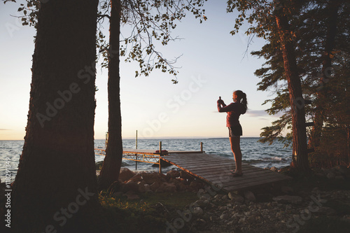 Caucasian girl photographing sunset and lake photo