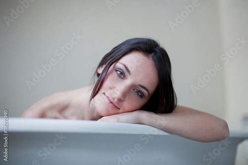 Caucasian woman leaning on side of bathtub photo