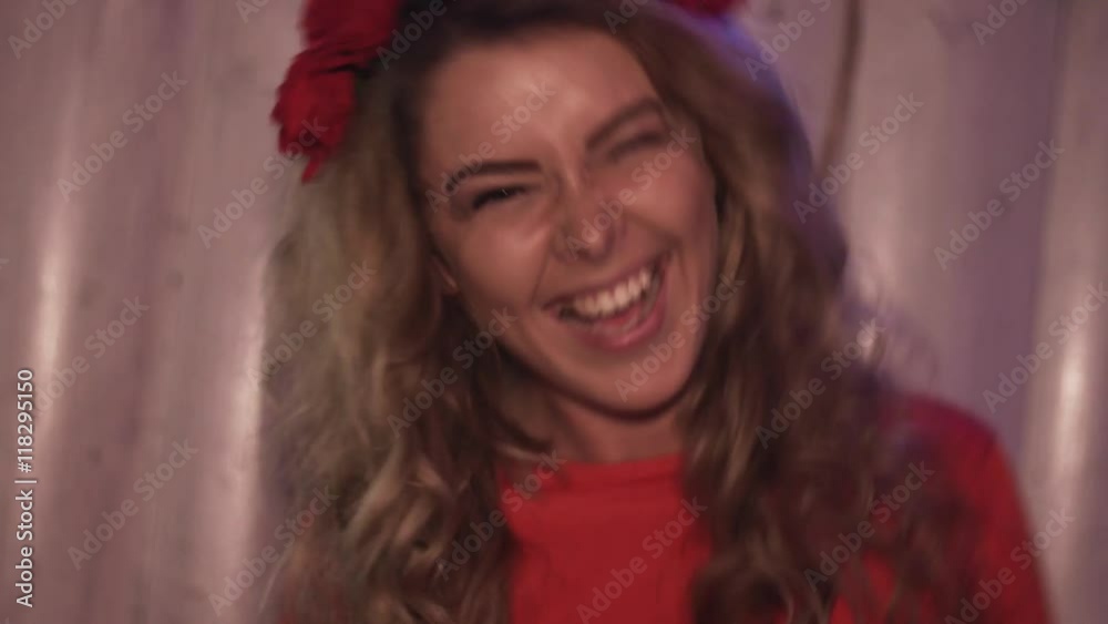 Dj girl in red dress dance at turntable in nightclub. Look in camera. Headphones. Red flower rim on head Dj girl in red dress dance at turntable in nightclub. Look in camera. Headphones. Red flower rim on head