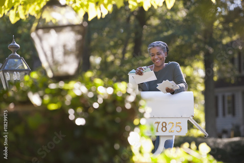 Mixed race woman reading mail at mailbox photo