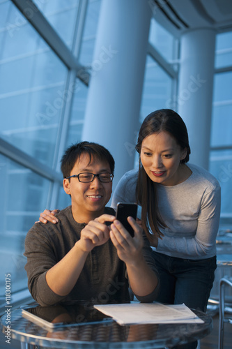 Asian couple looking at cell phone photo