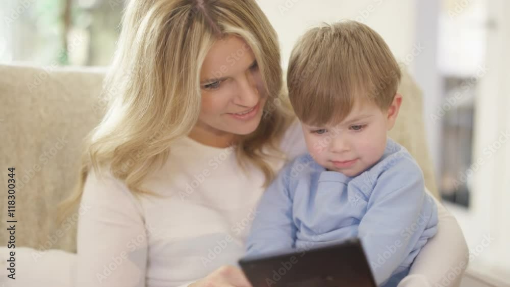 Mother & cute young son looking at computer tablet together at home Mother & cute young son looking at computer tablet together at home