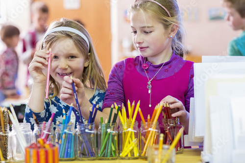 Caucasian girls choosing multicolor pencils in classroom