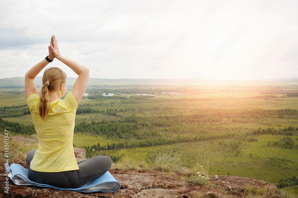 Woman in Lotus position on top of the mountain.