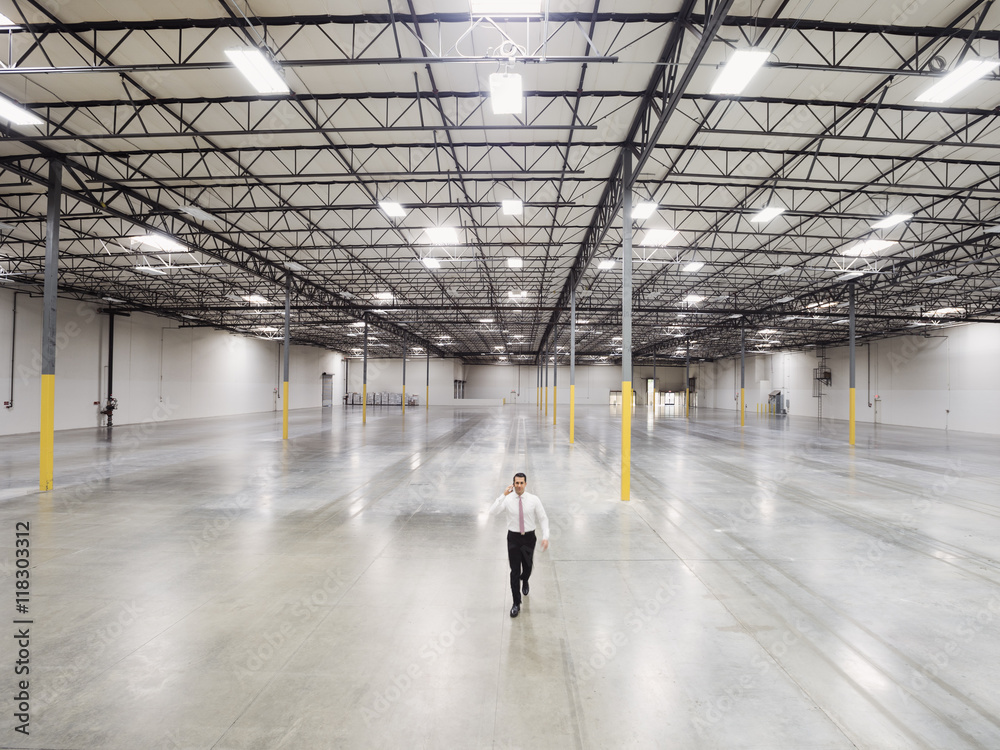 Caucasian businessman walking in empty warehouse Caucasian businessman walking in empty warehouse