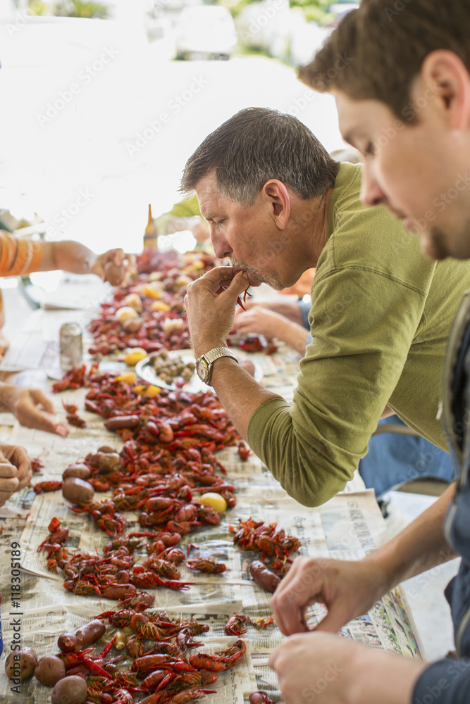 Caucasian men eating at crawfish boil Caucasian men eating at crawfish boil